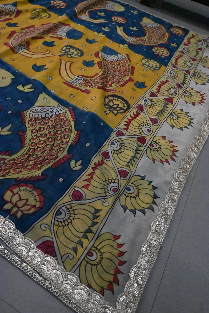 Floral and Matsya Theme : Yellow and Blue Authentic Pen Kalamkari on Banarasi Pure Georgette Saree with Fancy Lace Border  | SILK MARK CERTIFIED | SHOBITAM