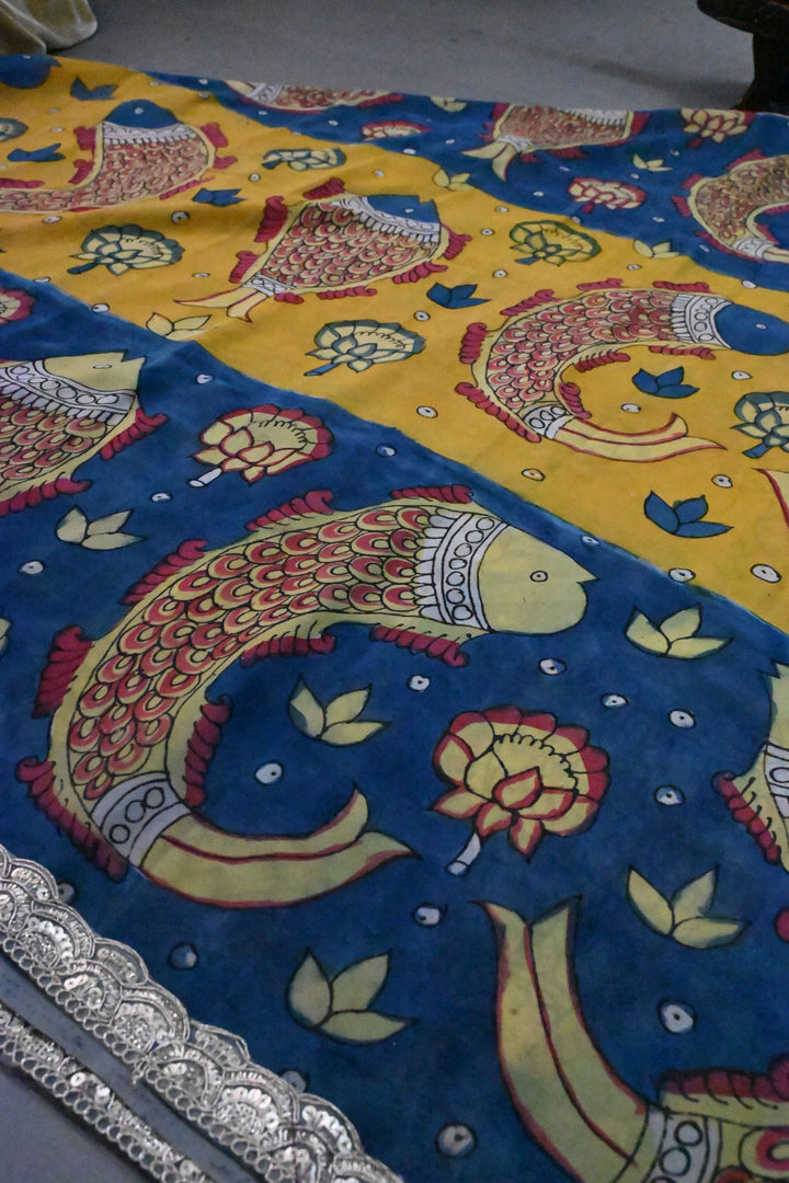 Floral and Matsya Theme : Yellow and Blue Authentic Pen Kalamkari on Banarasi Pure Georgette Saree with Fancy Lace Border  | SILK MARK CERTIFIED | SHOBITAM